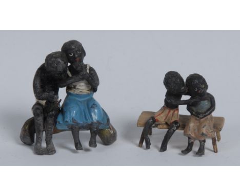 An early 20th century lead figure group, cast as a young black suitor embracing his sweetheart,  seated on a log, 5.5cm wide;