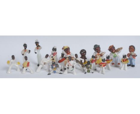 A set of four early 20th century bisque porcelain figures or cake decorations, slip cast as black musicians, each stands, pla