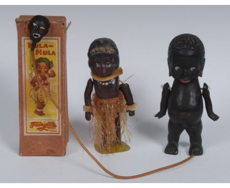 A mid 20th century clockwork toy, as a dancing native, 14cm high; a wooden doll, carved as a young black child, 14.5cm high; 