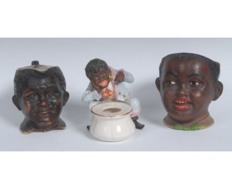 A Continental porcelain novelty inkwell, modelled as a comical black man beside a pot, flamboyantly dressed and wearing gold 