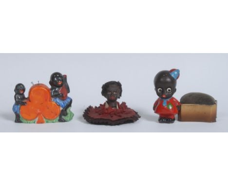 A Japanese novelty pin cushion, moulded with orange spade, flanked by two comical black children, one playing a mandolin, 7cm
