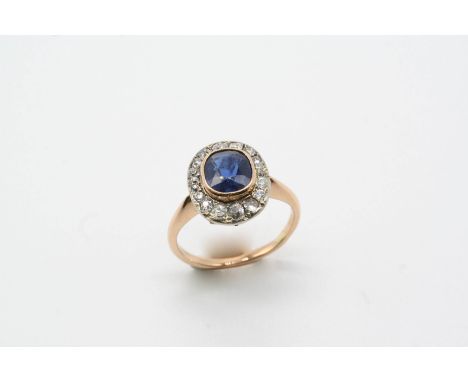 AN EARLY 20TH CENTURY SAPPHIRE AND DIAMOND CLUSTER RING the oval-shaped sapphire is set within a surround of old-cut diamonds