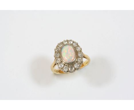 AN OPAL AND DIAMOND CLUSTER RING the oval-shaped solid white opal is set within a surround of old brilliant-cut diamonds, in 