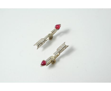 A PAIR OF ART DECO RUBY AND DIAMOND ARROW EARRINGS each mounted with baguette-cut and circular-cut diamonds, with a cabochon 