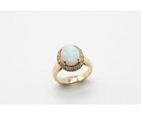 AN OPAL AND DIAMOND CLUSTER RING the oval-shaped solid white opal is set within a surround of circular-cut diamonds, in yello