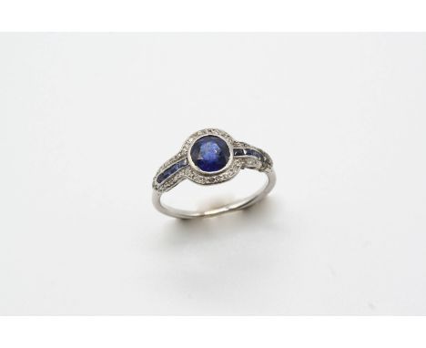 AN EARLY 20TH CENTURY SAPPHIRE AND DIAMOND CLUSTER RING the oval-shaped sapphire is set within a surround of calibre-cut sapp