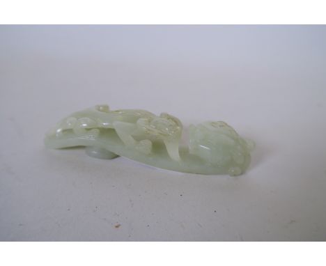 A Chinese carved celadon jade belt hook with dragon decoration, 4½" long 