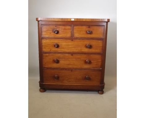 A Victorian mahogany chest of two short over three long drawers with carved corners and side columns, the drawers with turned