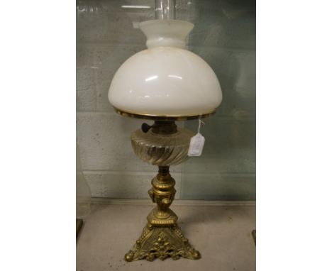 An ornate brass and glass oil lamp with opaque glass shade.