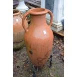 A terracotta urn on wrought iron stand.
