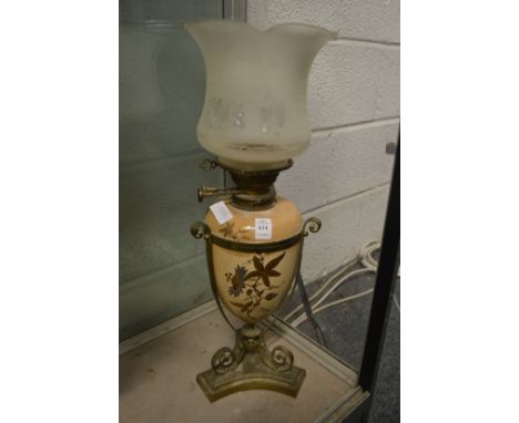 A brass and gilt decorated pottery oil lamp with decorative shade.