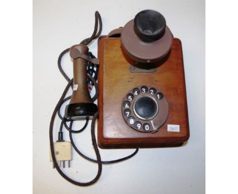 Vintage wood cased wall phone wood case, with attached rotary  dial, and fixed speaker piece, with hand set to side.