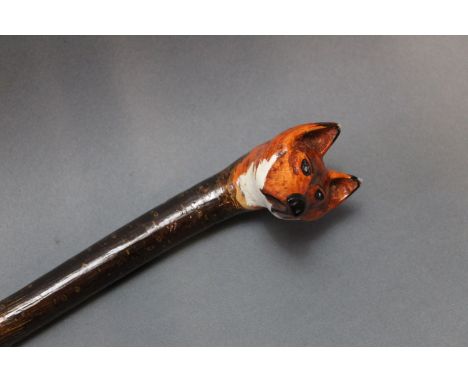 A hazel shafted walking stick with carved foxes head handle, overall length 116 cm.