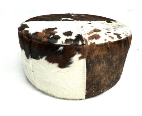 A circular pouffe upholstered in cow hide. Diameter 79cm.