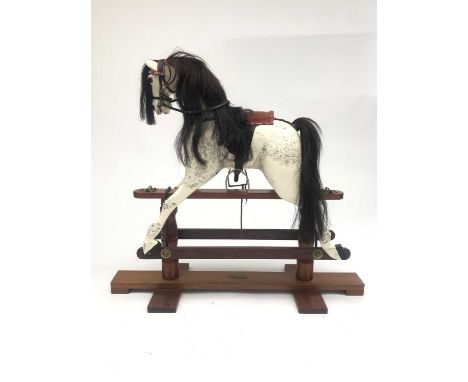A carved and painted rocking horse, late 20th century, dapple grey, on a mahogany base, length 107cm.