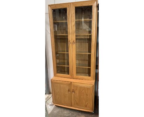An Ercol elm cabinet, with two glazed doors. Height 213cm, width 91cm, depth 44cm.Condition report: No condition issues.