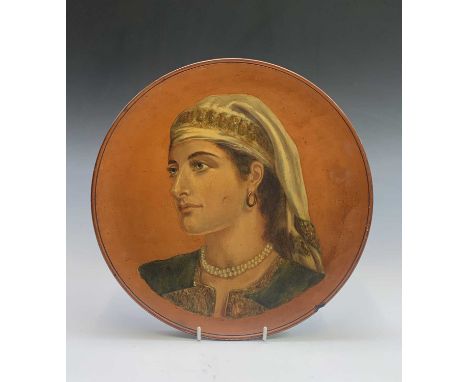 A Watcombe Torquay terracotta wall plaque, painted with a portrait of a woman, impressed mark to base, diameter 32cm. 