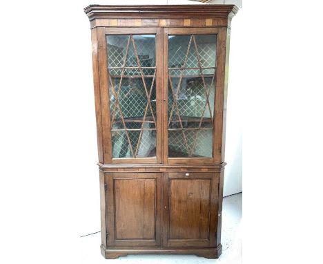A George III oak standing corner cupboard, with moulded cornice, the upper part with two astragal glazed doors enclosing shap