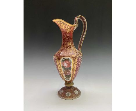 A mid 19th century Bohemian  cranberry cut overlay glass ewer with gilt and floral enamel decoration. Height 40cm.Condition r