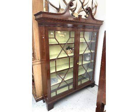 A George III mahogany bookcase cabinet, adapted, with swan neck pediment above two astragal glazed doors and now raised on br