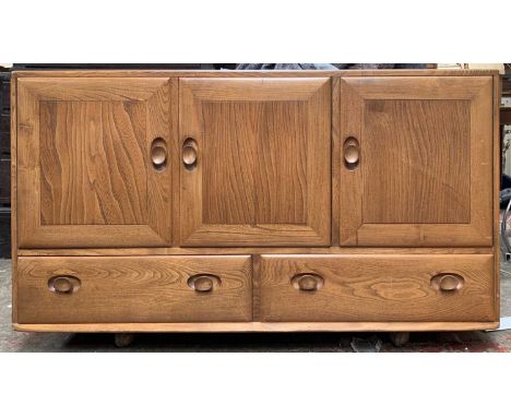 A mid century Ercol medium elm sideboard, fitted with three doors above two drawers. Height 76cm, width 129.5cm, depth 44cm.