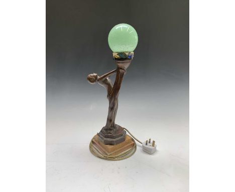 An Art Deco style table lamp modelled as a nude female holding a globe, signed. Height 47cm.