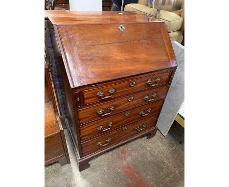 A George III mahogany writing bureau, with fall front enclosing drawers and pigeon holes, above four long drawers and raised 