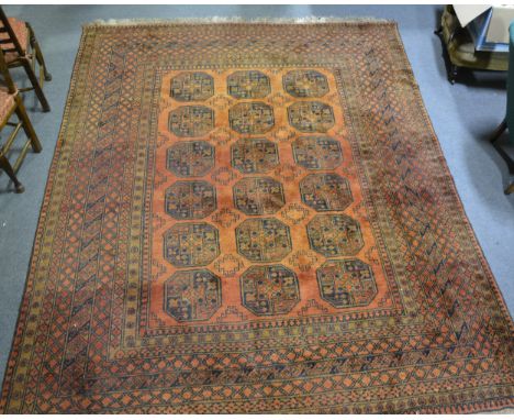 A Bokhara Afghan pattern carpet, with three rows of elephant foot gulls, on a rust field, bordered outlines, 3.26m x 2.59m.