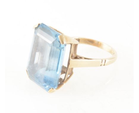 A synthetic blue stone dress ring, the rectangular step cut blue stone 20mm x 15mm, four claw set in a yellow metal mount, sh