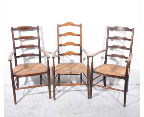 A pair of Arts &amp; Crafts style oak elbow charis, ladder-backs, rush seats, turned legs and rails, width 56cm and a similar