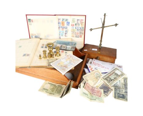 A balance scale with brass bell weights, a magnifying glass, postage stamp albums, banknotes etc 