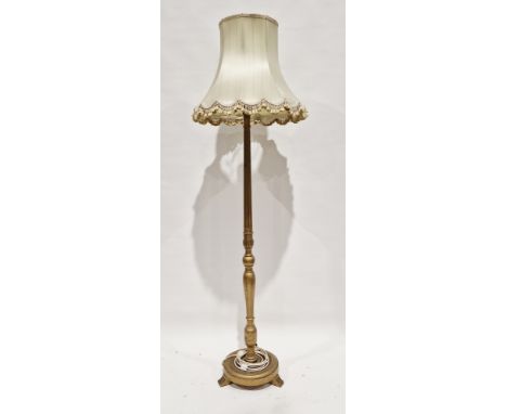 Giltwood standard lamp, the turned part fluted and part baluster column on a circular plinth base with three feet, with shade