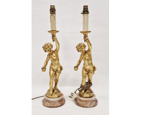 Pair of French-style gilt resin putti candlestick lamp bases, each modelled as a putto holding aloft a torch with a ball in r