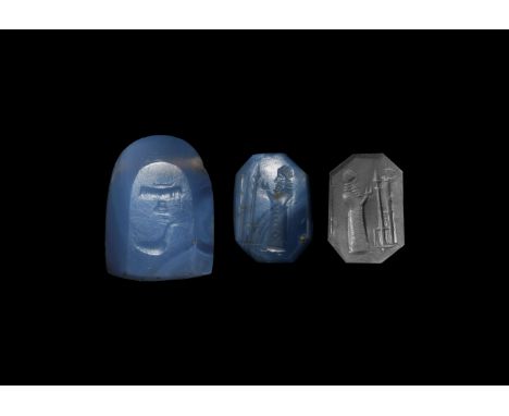 2nd millennium BC. A chalcedony facetted stamp seal with intaglio image of a robed figure approaching an altar with hands rai