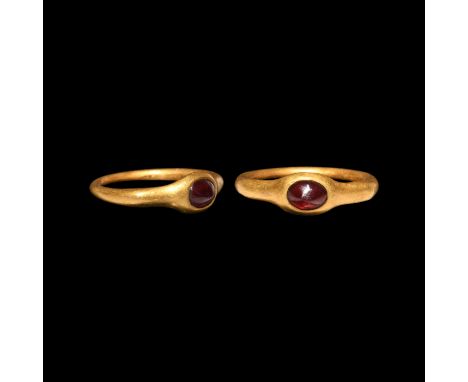 1st century AD. A gold finger ring with scooped shoulders, disc bezel with inset keeled cabochon garnet. Cf. Chadour, A.B., R