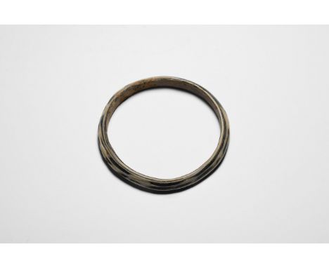 3rd-4th century AD. A black glass bangle with keeled profile, applied white trail decoration to the upper face.   40.1 grams,
