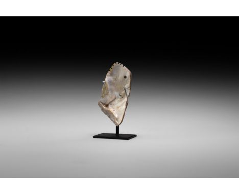 500 BC-500 AD. A carved shell panel with notched edges and drilled hole representing a beast-head with notched mane; mounted 