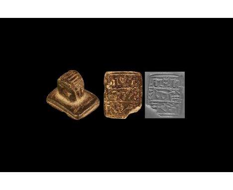 2nd millennium BC. A carved serpentine stamp seal with ribbed ring and stepped rectangular base; intaglio scene with figures 