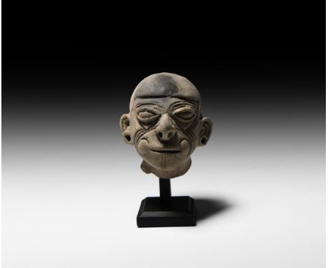 5th century BC-5th century AD. A ceramic figure head with exaggerated facial features, incised lines, pierced ears; mounted o