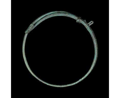 9th-12th century AD. A copper-alloy faux-twisted neck-ring with stylised snake's head terminal and tail terminal; round-secti
