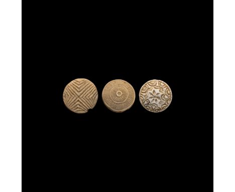 3rd-2nd millennium BC. A group of three ceramic seals, two pierced, with foliage, floral, hexafoil and other designs.   23.8 