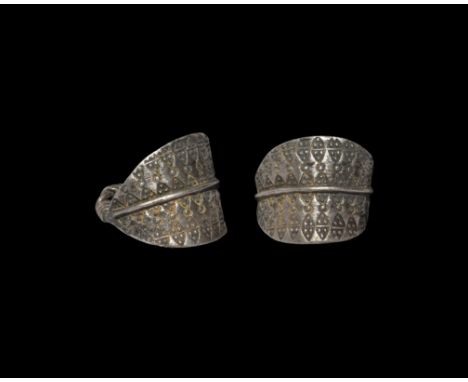 10th-12th century AD. A sheet silver ring with plaque extending to twisted rod finials, raised median band flanked by stamped