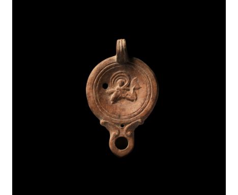 1st-2nd century AD. A ceramic oil lamp with short nozzle, volute scroll to each side, the discus with Cupid riding a dolphin 