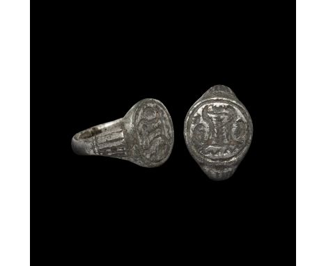 13th-15th century AD. A silver ring with D-section hoop, fluted shoulders, discoid bezel with a central column flanked by S-c