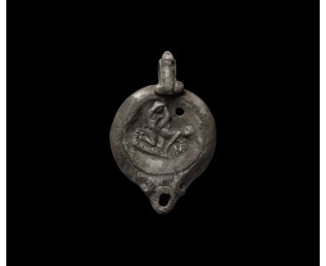 1st-2nd century AD. A crystalline silver oil lamp with short spout, volute scrolls to each side, a large phallus resting on t