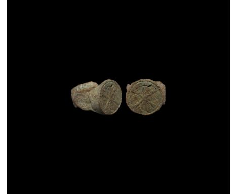 6th-7th century AD. A bronze finger ring with tongue-shaped panels to the shoulders, disc bezel with low-relief chi-rho chris