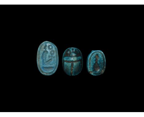 Late Period, 664-332 BC. A group of three glazed composition amulets comprising: two scaraboids with intaglio bust to the und