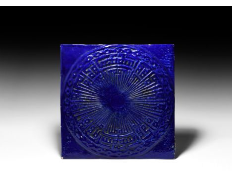 19th-20th century AD. A large square ceramic wall tile with deep blue glazed surface, low-relief sunburst motif with band of 