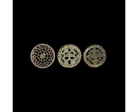 23rd-20th century BC. A group of three discoid openwork bronze seals comprising: one with central cross motif with zig-zag ed