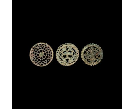 23rd-20th century BC. A group of three discoid openwork bronze seals comprising: one with central cross motif with zig-zag ed